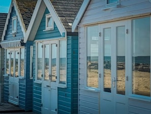 Une rangée de charmantes maisons de vacances en bord de mer, dotées de grandes fenêtres et d’un toit en pierre.