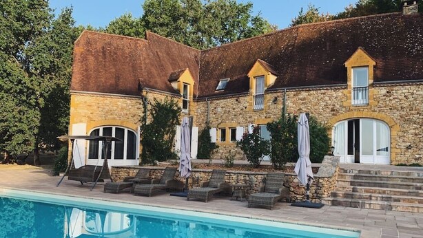 Un bâtiment en pierre doté d’une piscine, d’un espace extérieur aménagé et d’un escalier menant à une porte.