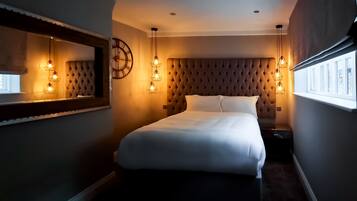 A bedroom with a tufted headboard, a large mirror, and pendant lights.