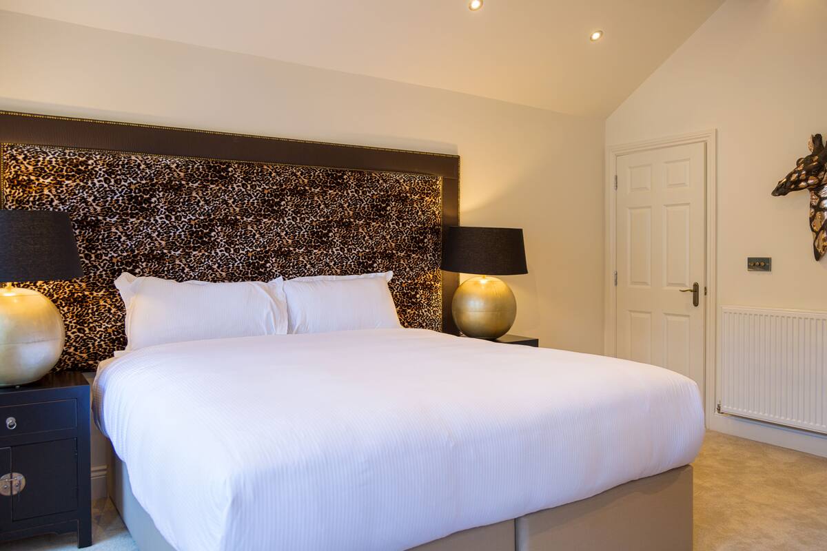 A bedroom with a large bed, two bedside tables, and a leopard print headboard.