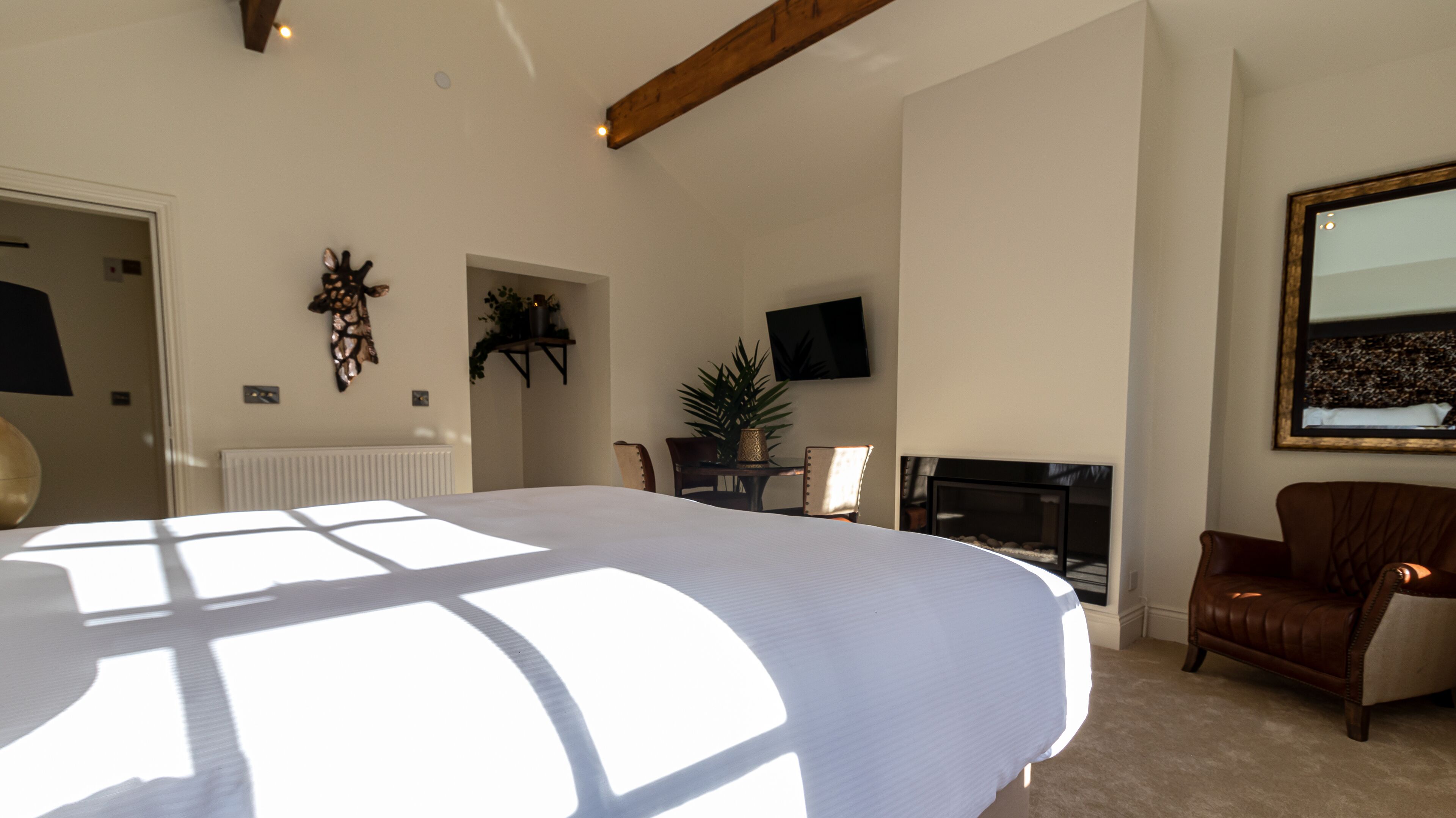 Une chambre avec un grand lit, une cheminée, une télévision et un fauteuil.