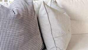Una sala de estar moderna con un sofá beige y dos almohadones.