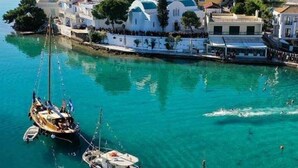 A coastal town with boats docked at a pier, surrounded by buildings with domed roofs. - Amazing 2-bedroom Apartment Close to all Amenities (Ermionida)