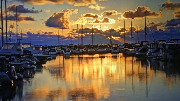 A marina with boats docked, calm water reflecting the sky, and a sunset in the background. - Trendy! Pro Cleaned, Self Check In - Sleeps 10 (Pleasant Prairie)