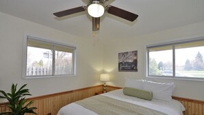 A bedroom with a bed, a ceiling fan, two windows, a nightstand, a lamp, and a framed picture on the wall. - Trendy! Pro Cleaned, Self Check In - Sleeps 10 (Pleasant Prairie)