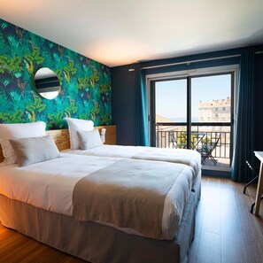 Una habitación de hotel con una cama grande, un balcón con vistas y un papel tapiz tropical.