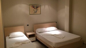 A hotel room with two single beds, a nightstand, and a wall-mounted artwork. - Denta Hotel (Orikum)
