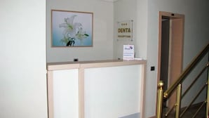 A reception area with a sign for 'DENTA RECEPTION' and a framed picture of white flowers on the wall. - Denta Hotel (Orikum)