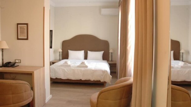 A hotel room with a large bed, a desk with a lamp, and a chair. - Hermes Hotel (Tirana)