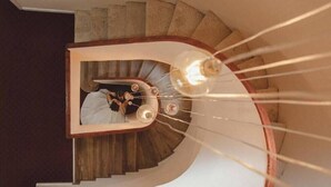 A spiral staircase with a wooden handrail and a light fixture at the top. - Hermes Hotel (Tirana)