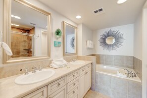 A modern bathroom with two sinks, a large mirror, a sunburst wall decoration, and a separate bathtub. - P4-0709 2B Island View Elite Condo @ Portofino! (Pensacola Beach)