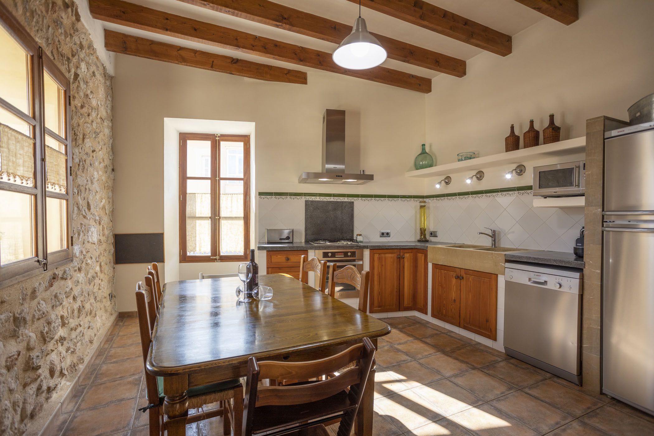 A kitchen with wooden beams, a dining table, and modern appliances.
