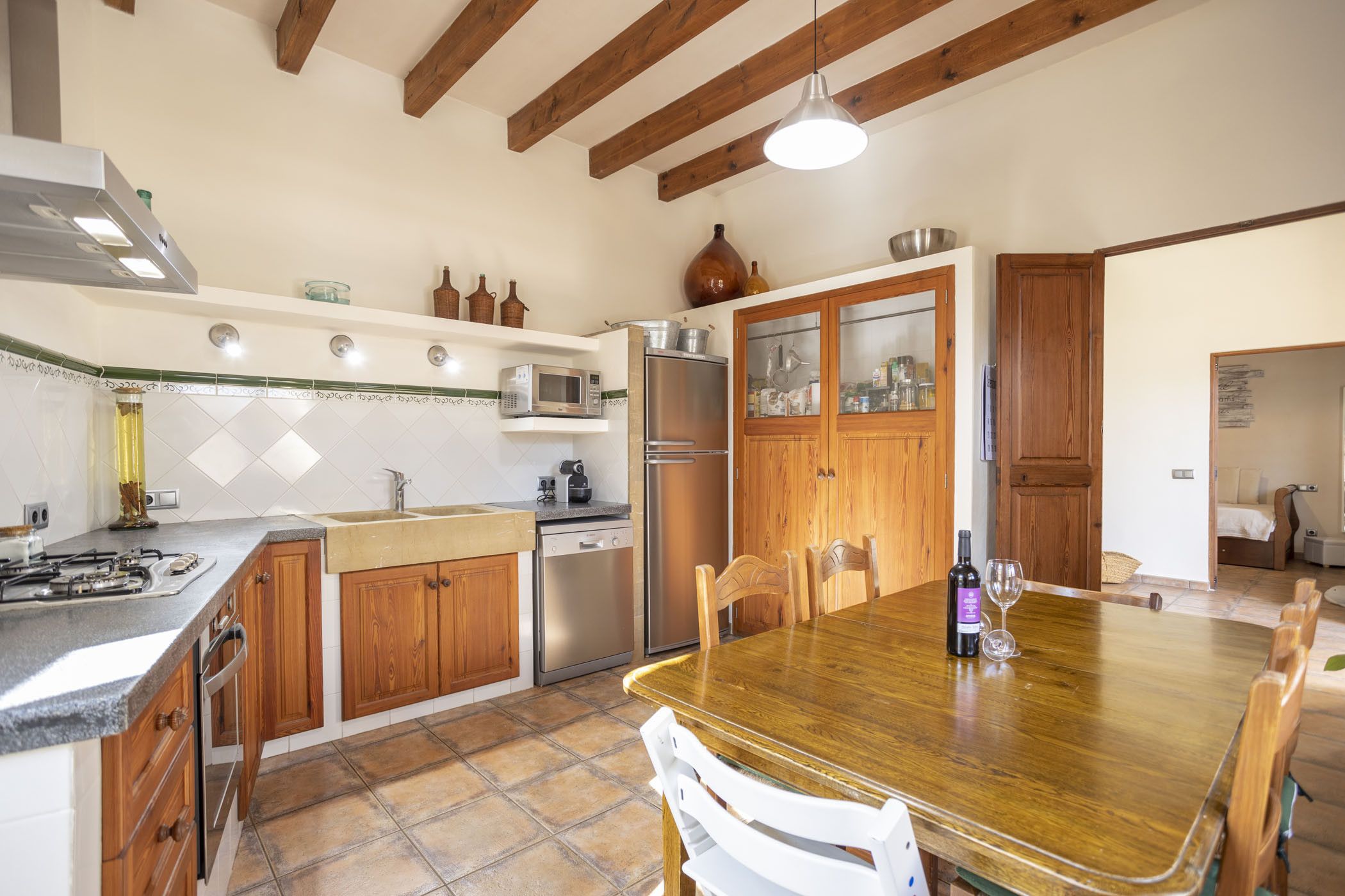Une cuisine avec des meubles de rangement en bois, un réfrigérateur en acier inoxydable, un four à micro-ondes et une table à manger avec des chaises.