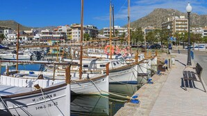 Un port esportiu amb embarcacions amarrades, un passeig pavimentat i edificis al fons.