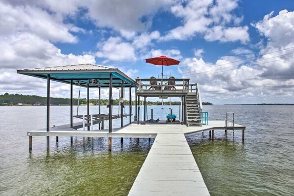 Une jetée s’avançant dans un lac, avec un espace de repos abrité et un parasol rouge.