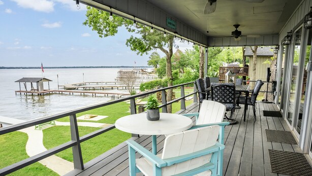 A covered deck with outdoor seating, a view of the water, and a dock area. - Lakefront w/ Dock, 300mb WIFI, Theater, Arcade (Tool)
