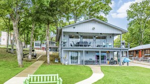 A two-story building with a balcony, a covered patio, and a green bench in front. - Lakefront w/ Dock, 300mb WIFI, Theater, Arcade (Tool)