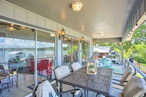 Une terrasse extérieure avec une table et des chaises, des portes vitrées donnant sur l’intérieur et une vue sur l’extérieur.
