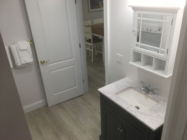 A bathroom with a white sink, dark cabinets, and a white door.