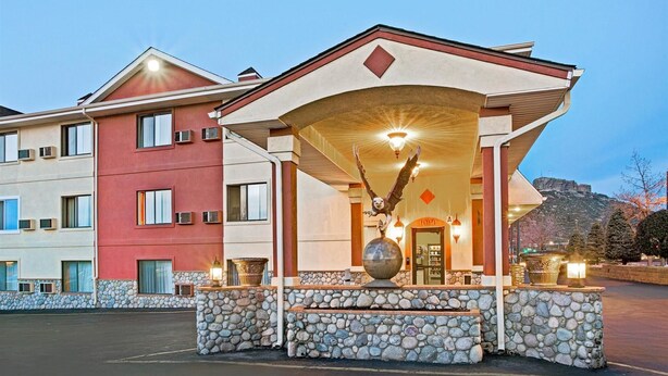 A hotel entrance with a stone facade, a large bird sculpture, and a mountain backdrop. - Oyo Hotel Downtown Castle Rock (Castle Rock)