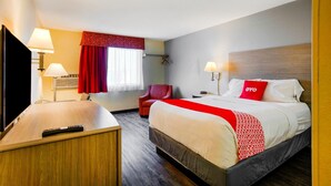 A hotel room with a bed, a desk, a chair, a TV, and a window with curtains. - Oyo Hotel Downtown Castle Rock (Castle Rock)