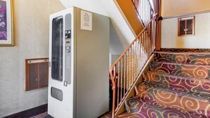 A room with a vintage air conditioner, a patterned carpeted staircase, and a framed picture on the wall. - Oyo Hotel Downtown Castle Rock (Castle Rock)