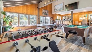 A spacious room with a foosball table, a pool table, and large windows offering a view of the outdoors. - Season's Four 193-Mountain retreat close to town, shops, restaurants & more! (Mammoth Lakes)