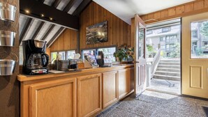 A wooden counter with a coffee machine, a framed picture, and a view of a building outside. - Season's Four 193-Mountain retreat close to town, shops, restaurants & more! (Mammoth Lakes)
