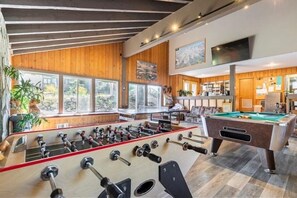 A spacious room with a foosball table, a pool table, and large windows offering a view of the outdoors. - Season's Four 193-Mountain retreat close to town, shops, restaurants & more! (Mammoth Lakes)