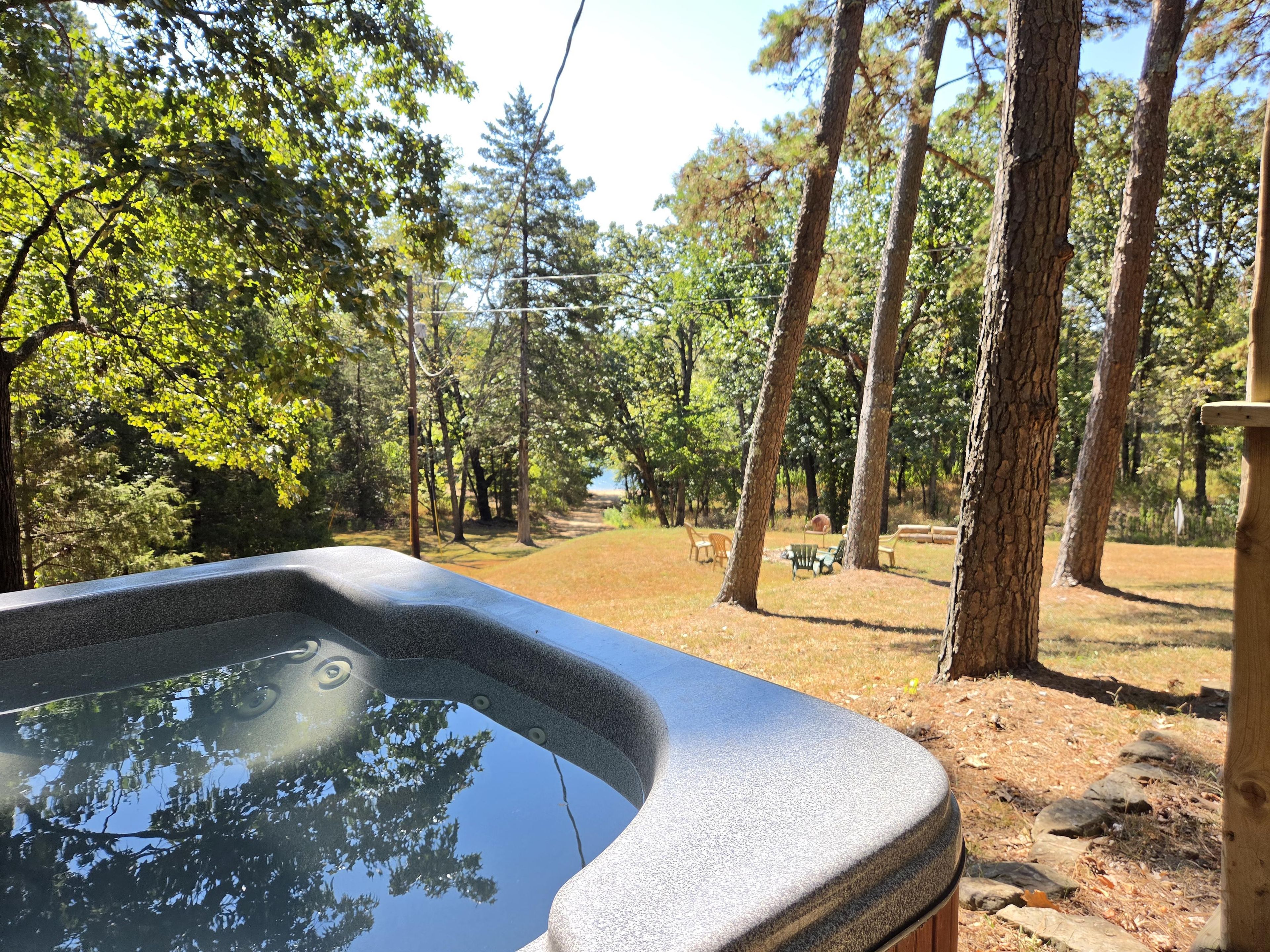 A hot tub with a view of a wooded area and a picnic table.
