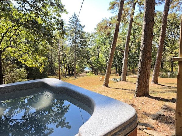 A hot tub with a view of a wooded area and a picnic table.
