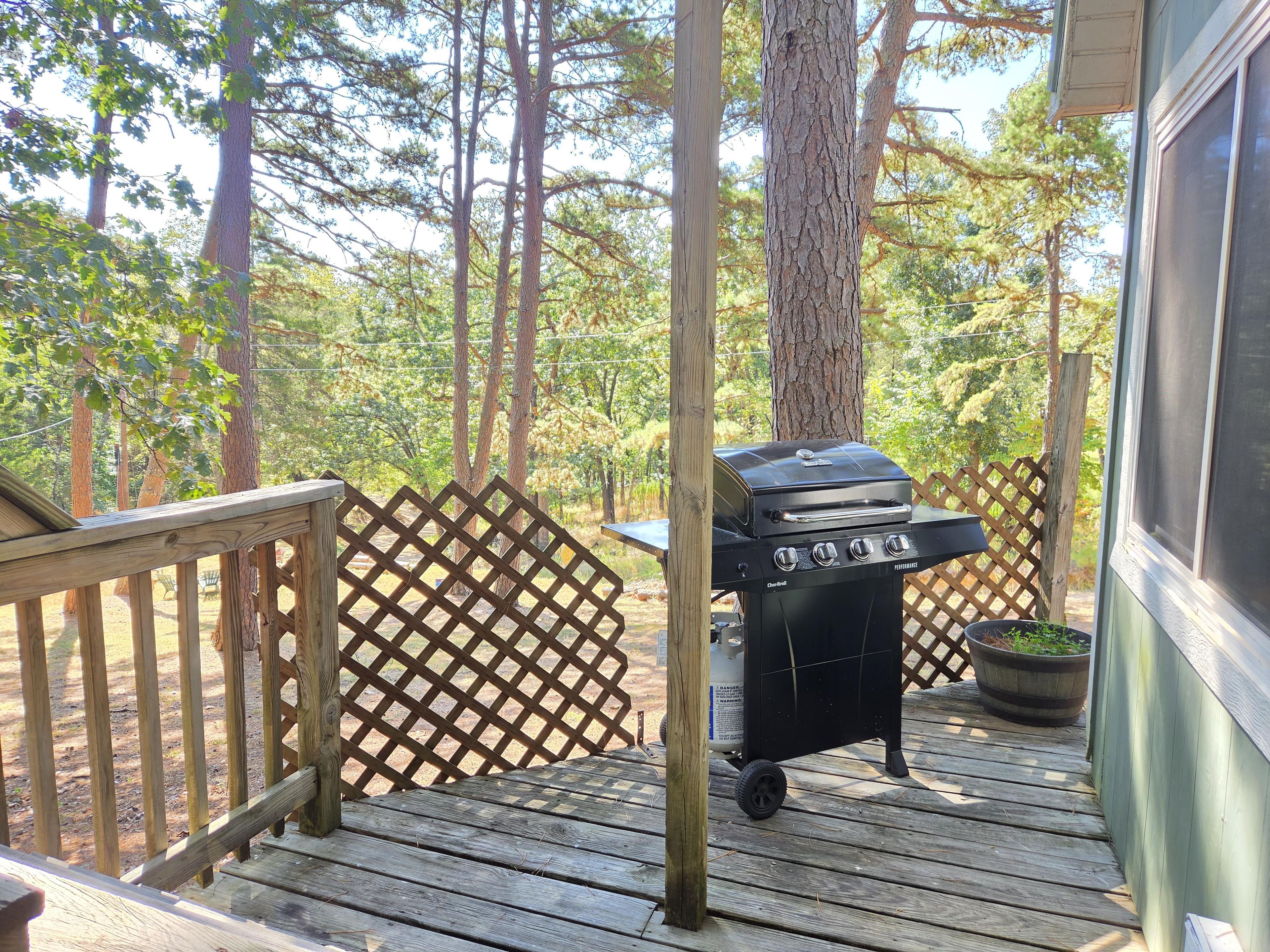 A wooden deck with a barbecue grill, a wooden fence, and a potted plant.