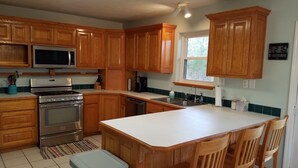 A kitchen with wooden cabinets, stainless steel appliances, a large island, and a window.