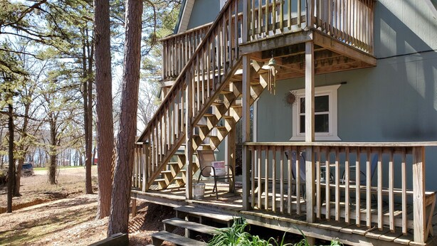A two-story wooden house with a balcony and a staircase leading to the upper floor.