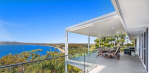 A modern balcony with a glass railing overlooking a coastal landscape. - Randall Drive No 64 - Magnificent Views - Pool - Air con - WiFi - The list goes on! (Salamander Bay)