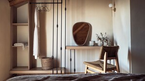 Une chambre avec un lit en bois, une chaise, une étagère avec un miroir et un portant à vêtements.