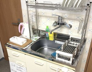 Una cocina con un lavamanos, escurreplatos y una cafetera.