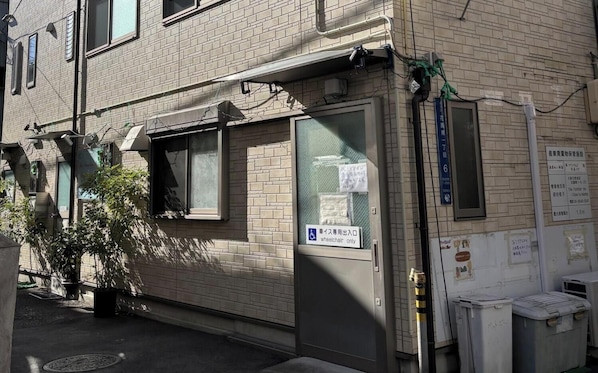 Ein Gebäude mit barrierefreiem Eingang, einem kleinen Fenster und einem Schild mit japanischen Schriftzeichen.