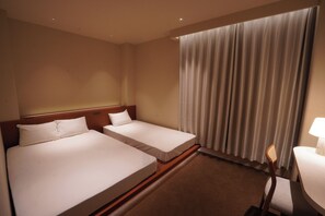 Habitación de hotel con dos camas individuales, cabecero de madera, ventana con cortinas, una mesita de noche con lámpara y una silla.