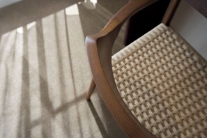 A close-up of a wooden chair with a woven seat.