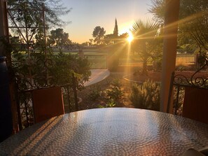Une terrasse dotée d’une table à surface texturée, entourée de rampes en métal et de plantes.