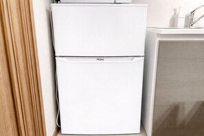 A white Haier refrigerator and a white sink in a bathroom.