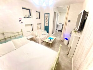Ett hotellrum med en säng, ett skrivbord, en stol, en tv och ett badrum som syns genom en dörr.