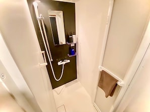 Een compacte, smalle badkamer met een douche, een spiegel en een handdoekhouder.