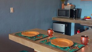 Una cocina con dos taburetes, un microondas y un lavabo.
