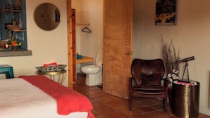 Un dormitorio con cama, techo de madera, una puerta que da al baño y un cartel en la pared.