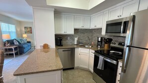 A modern kitchen with white cabinets, stainless steel appliances, and a granite countertop. - 2 Bedroom / 2 Bath Ground Level With a Heated Pool (Holmes Beach)