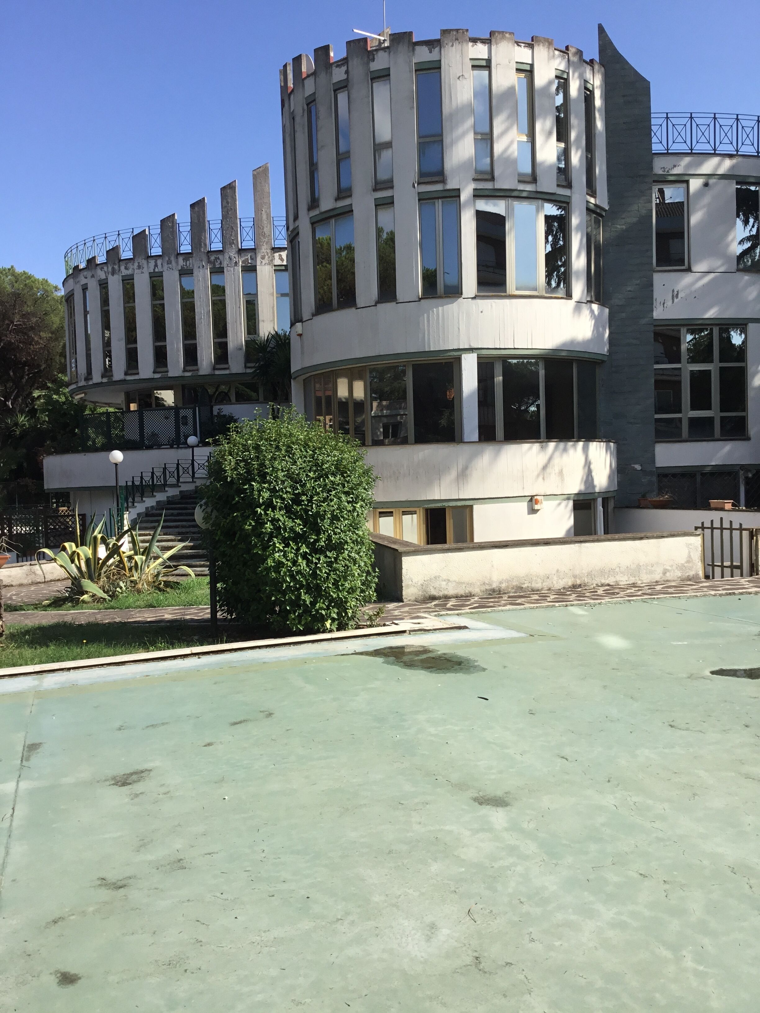 Un immeuble à plusieurs étages doté d’une façade incurvée, de grandes fenêtres et d’un balcon.