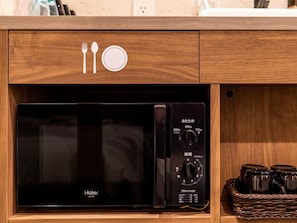En mikrovågsugn från Haier med en kontrollpanel, en låda i ett träskåp och en korg av rotting med burkar.
