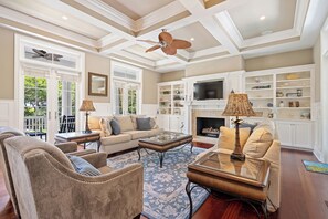 A spacious living room with a sofa, armchairs, a coffee table, and a fireplace.